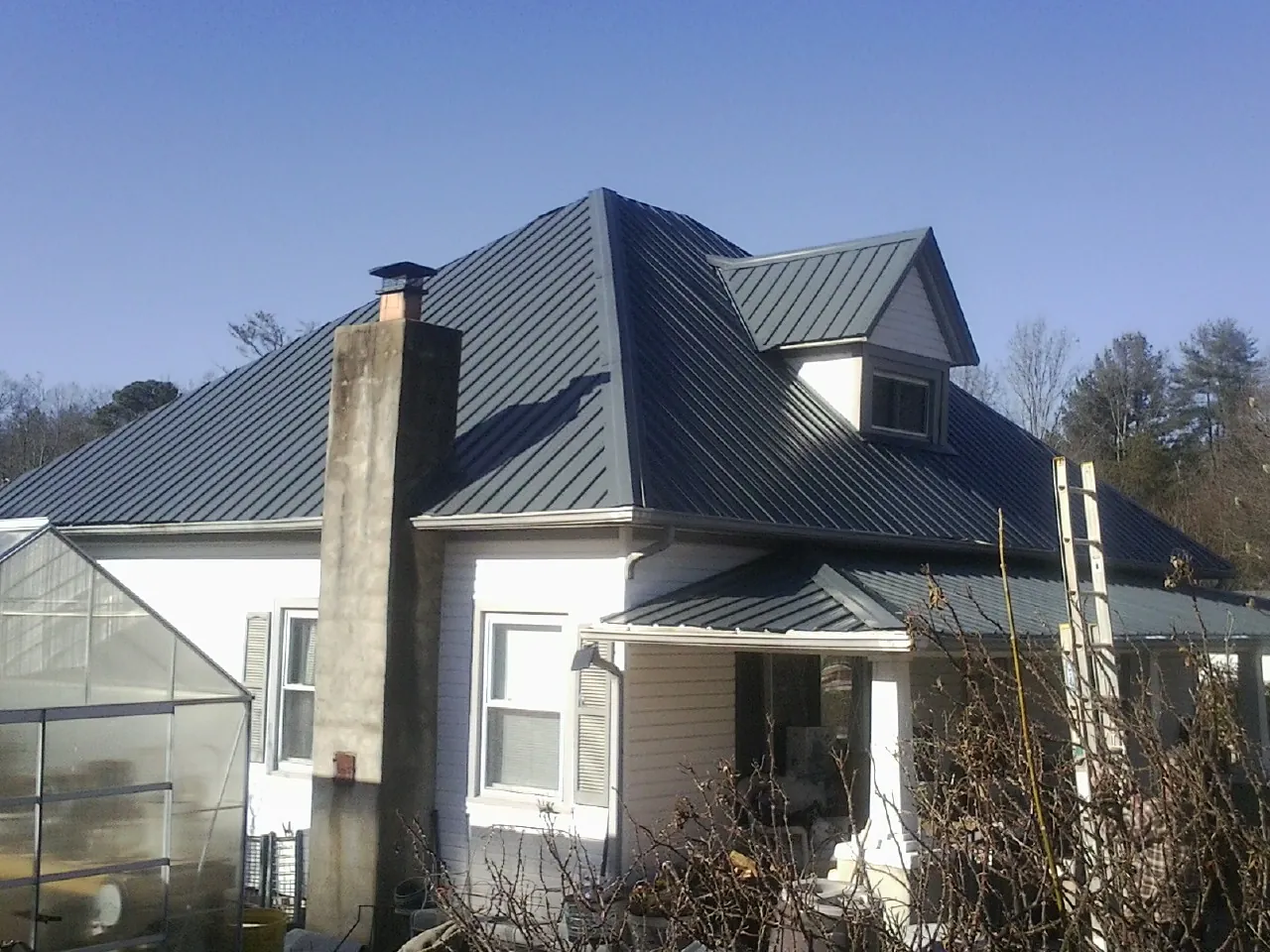 Dark blue standing seam metal roof on a white farmhouse with dormer — Slate & Tile Roof Repair by Roofing Brothers in Flagstaff