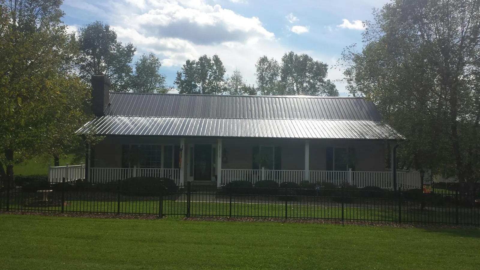 Gray metal roof on a brick ranch with a full width front porch — Gutter Guard Installation work by our crew in Flagstaff