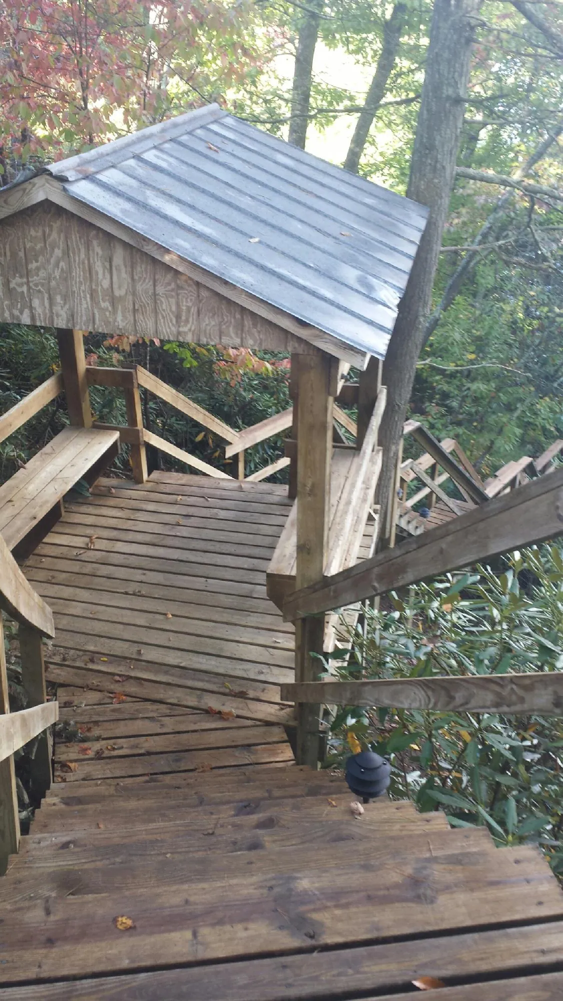Metal roofed shelter over wooden steps on a wooded walkway — Skylight Repair & Installation work by our crew in Flagstaff