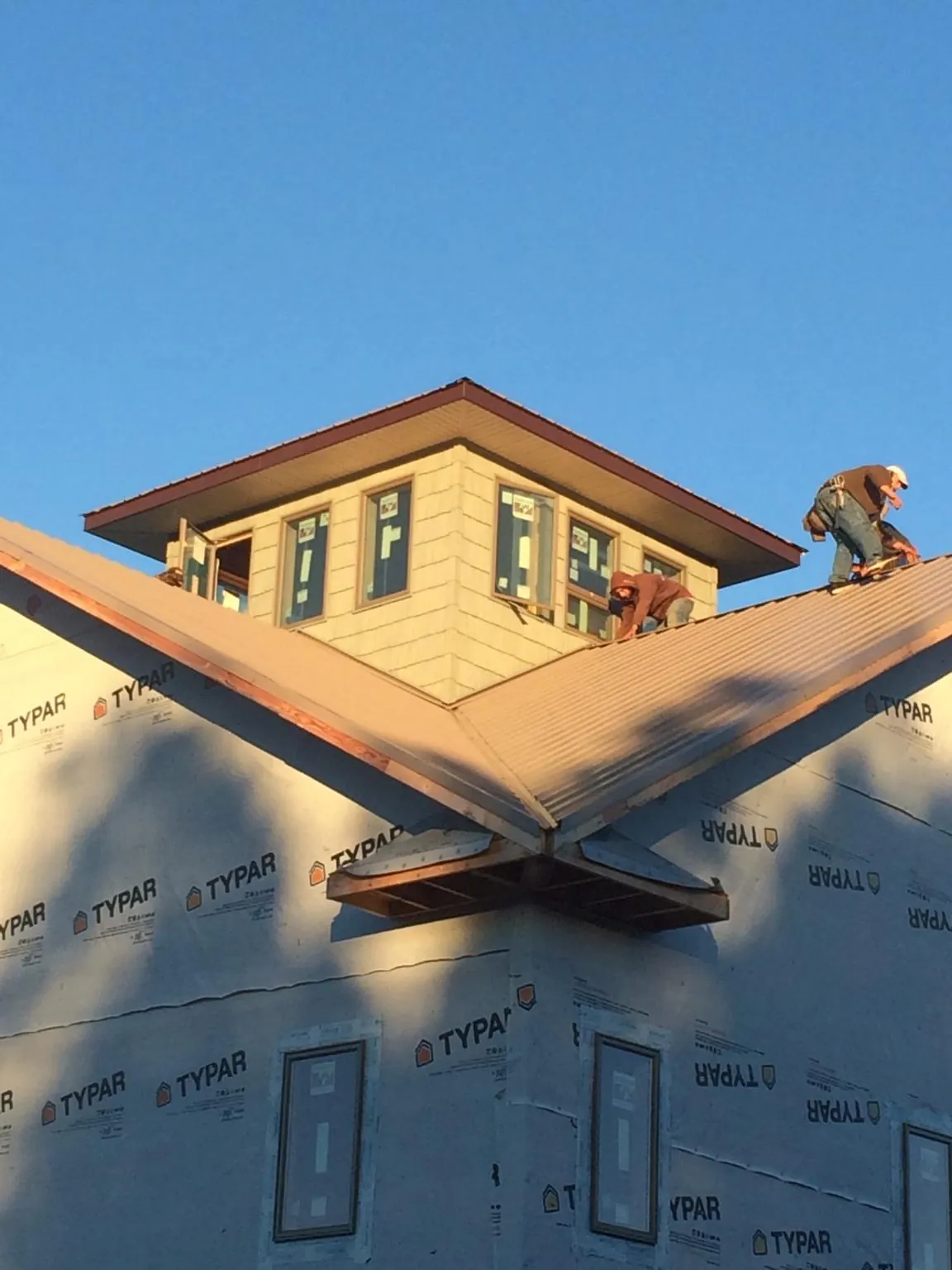 Roofers working around a rooftop cupola on a new metal roof at sunset — Roof Waterproofing in Flagstaff by Roofing Brothers